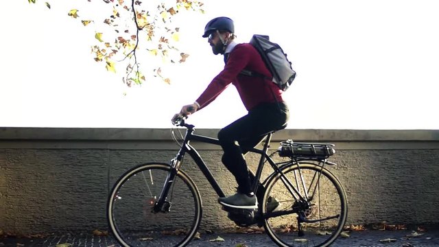 Businessman commuter with electric bicycle traveling from work in city. Slow motion.