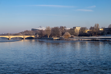 Ansicht vom teilweise gefrorenen Fluss "Weisse Elster"mit Baeumen und einem Wehr bei blauen Himmel