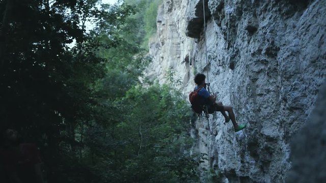 male climber down the rope along the cliff