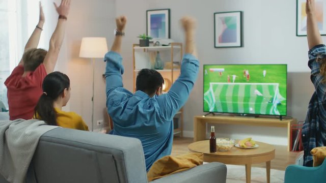 At Home Diverse Group of Sports Fans Watches Important Soccer Match on TV, They Cheer for the Team, Celebrate Victory after Team Scoring Beautiful Winning Goal. 