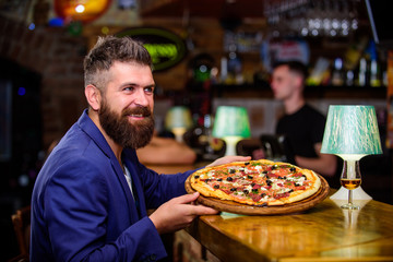 Man received delicious pizza. Enjoy your meal. Cheat meal concept. Hipster hungry eat italian pizza. Pizza favorite restaurant food. Fresh hot pizza for dinner. Hipster client sit at bar counter - obrazy, fototapety, plakaty