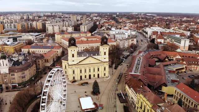 Aerial shot flying over a ferris wheel and main square of Debrecen, Hungary, towards the Reformed Great Church on a beautiful Christmas Day