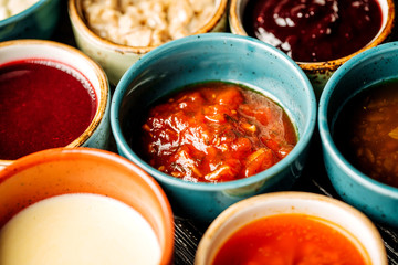 Set of different sauces on black wooden background.