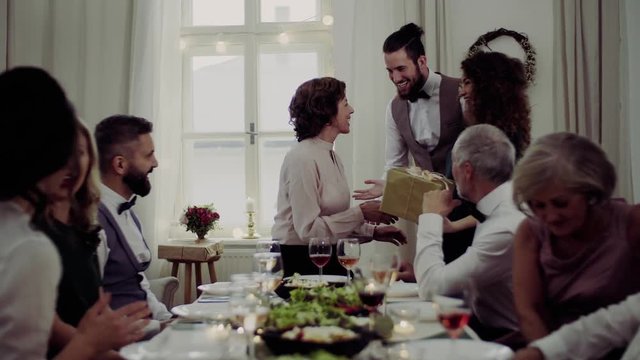 A senior mother celebrating birthday with family and recieving a gift, party concept.