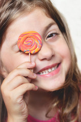 Little girl with lollipop over her eye, making faces and having fun