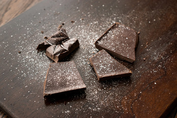 Bitter Chocolate Pieces with Sea Salt on Dark Wooden Surface.