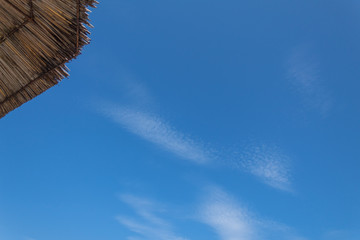 clear summer sky and straw umbrella tip