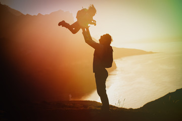 happy father and little daughter travel in mountains at sunset