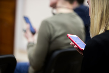 business people hands typing on smart phone during the seminar at conference room