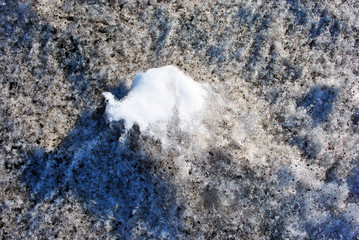 Dirty melting snow with clean white spot in center, early spring, natural background, close up...