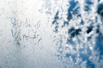 The inscription: goodbye, winter. On a frozen winter window in frosty patterns