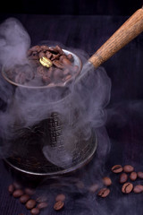 Golden coffee bean on freshly roasted ones in a Turkish coffee pot against the dark background
