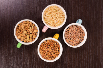 Uncooked rice, lentils and buckwheat in cups close up