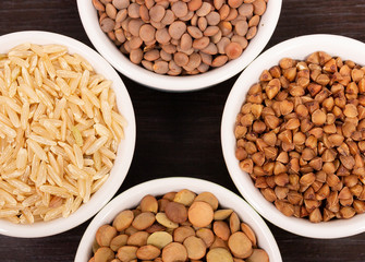 Uncooked rice, lentils and buckwheat in cups close up
