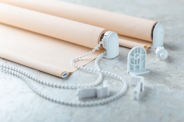 The roller blind lies on a white or gray concrete surface.