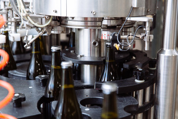 Glass bottles on the automatic conveyor line at the champagne or wine factory. Plant for bottling alcoholic beverages.