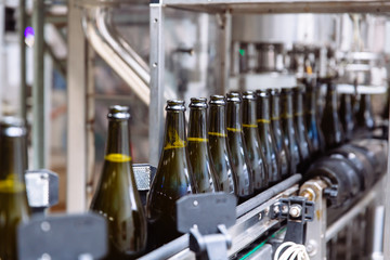 Glass bottles on the automatic conveyor line at the champagne or wine factory. Plant for bottling alcoholic beverages.