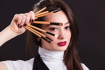 Makeup artist with brushes in hand on a black background