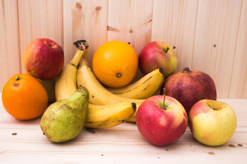 Naklejka na ściany i meble Various fruits apples, bananas, oranges, pomegranates on natural wooden background. Healthy food