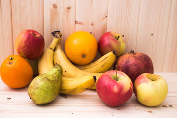 Various fruits apples, bananas, oranges, pomegranates on natural wooden background. Healthy food