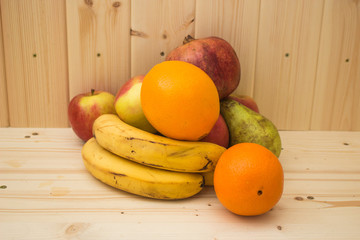 Various fruits apples, bananas, oranges, pomegranates on natural wooden background. Healthy food