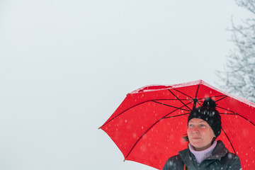 Beautiful cheerful woman under umbrella enjoying snow
