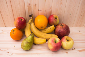 Various fruits apples, bananas, oranges, pomegranates on natural wooden background. Healthy food