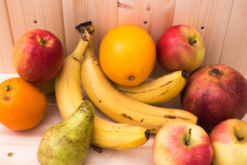 Various fruits apples, bananas, oranges, pomegranates on natural wooden background. Healthy food