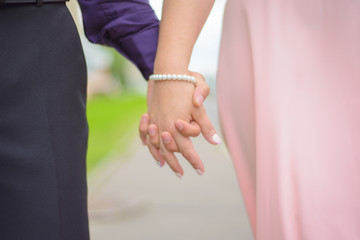 wedding: hands of the newlyweds on the background of the road