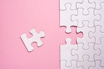 Incomplete white jigsaw puzzle pieces on pink background