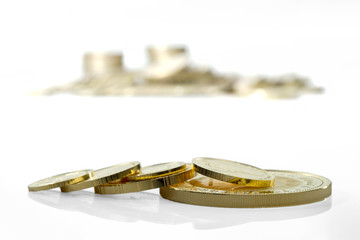 Several gold coins on the background of unsharp image of a large pile of gold coins. Isolated on a white background.