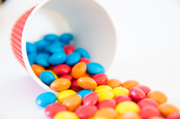multi-colored round candies dragees spilled out of an inverted paper cup