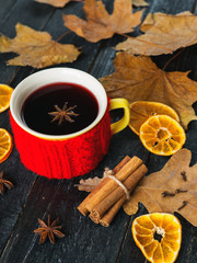 Mulled wine with spice and orange on wooden background with autumn leaves