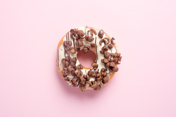 Fresh chocolate donut or doughnut decorated wit chocolate cereal on pink pastel table top