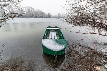 Naklejka premium Danube island (Šodroš) near Novi Sad, Serbia. Colorful landscape with snowy trees, beautiful frozen river. A boat covered with snow.