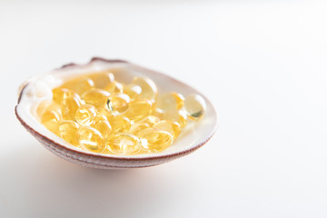 A side view of a handful of transparent yellow-golden tablets lies in a clamshell on a white isolated background.