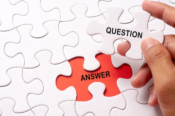 Hand holding piece of jigsaw puzzle with word question & answer