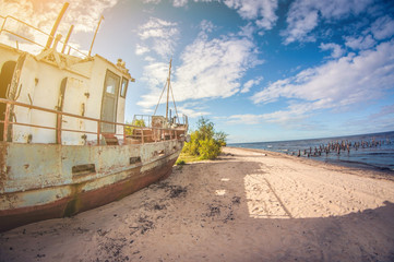Obraz premium abandoned boat on the sandy shore of a lake on a sunny day. distortion perspective fisheye lens