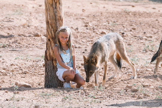 Little blonde girl with wolf in zoo