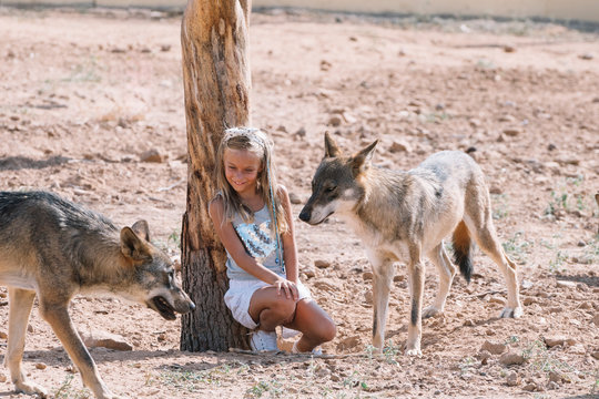 Little blonde girl with wolf in zoo