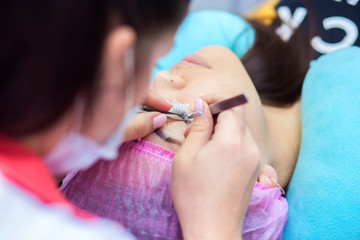 The master in eyelash extension works in beauty shop with the client. The girl increases eyelashes in studio