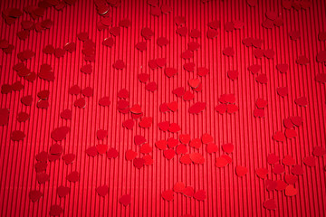 Beautiful Valentines Day background with red ribbed paper with heart-shaped confetti