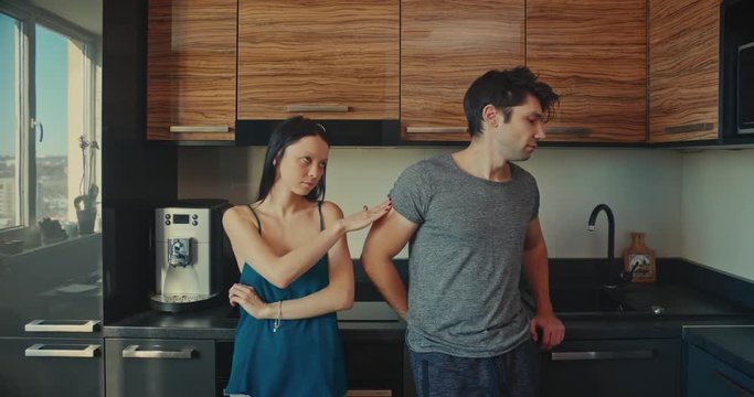 Young couple in an argument in a kitchen in the morning. They make peace start kissing.