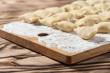 Raw dumplings on wooden cutting board, is ready to boil. Also known as Vareniks. Ukrainian traditional cuisine