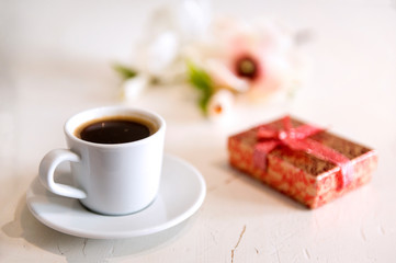 Cup of black coffee, a box with a bow on a white background