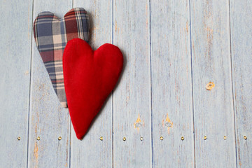 Two textile hearts in vintage style on a light wooden background.