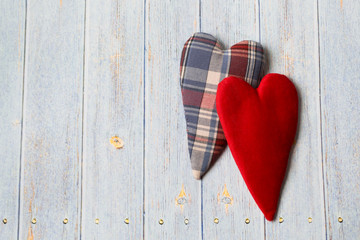 Two textile hearts in vintage style on a light wooden background.