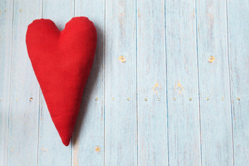 One red textile heart in vintage style on a light wooden background. Place for text.