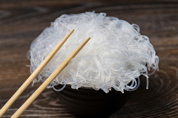 Rise noodles in black bowl on wooden background