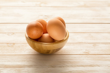 Bowl with egs on white wooden background